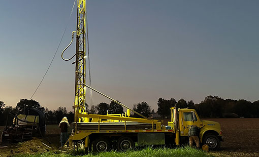 well digging truck in field at night